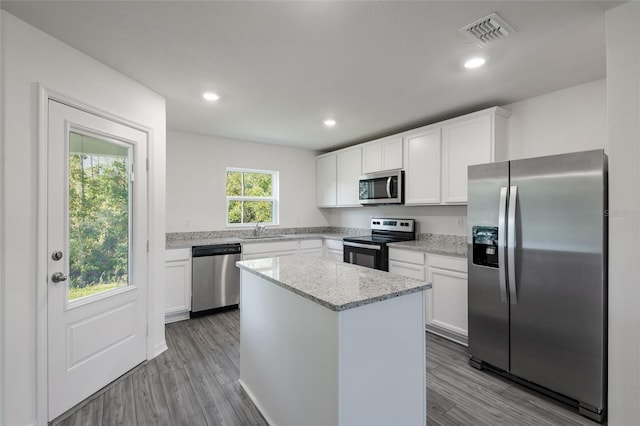 kitchen featuring white cabinetry, sink, a center island, stainless steel appliances, and light stone counters