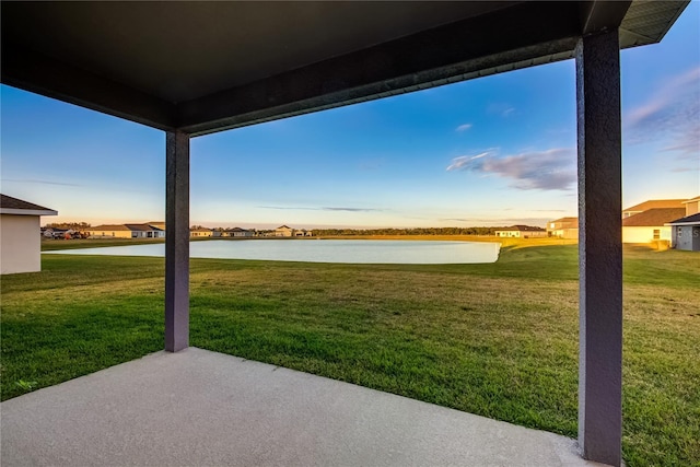 yard at dusk with a water view and a patio