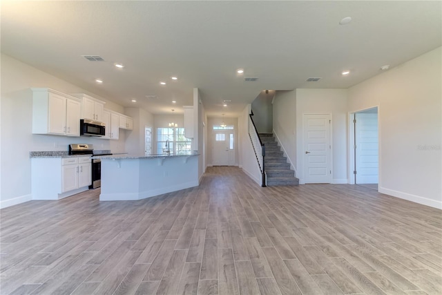 kitchen featuring stainless steel electric range, a notable chandelier, light stone countertops, white cabinets, and light wood-type flooring