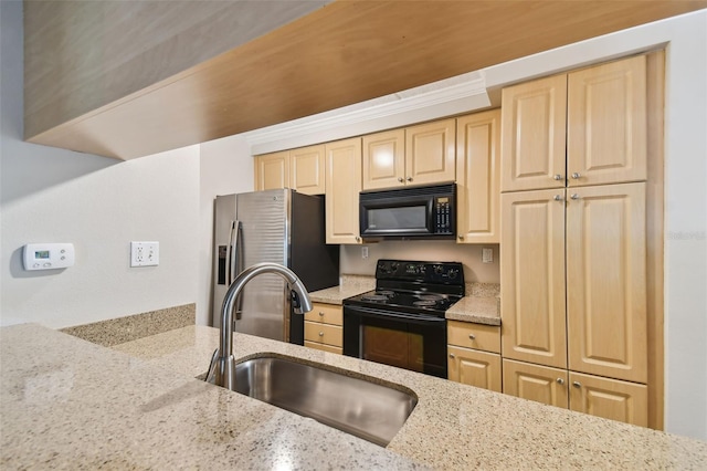 kitchen featuring black appliances, light brown cabinetry, a sink, and light stone countertops