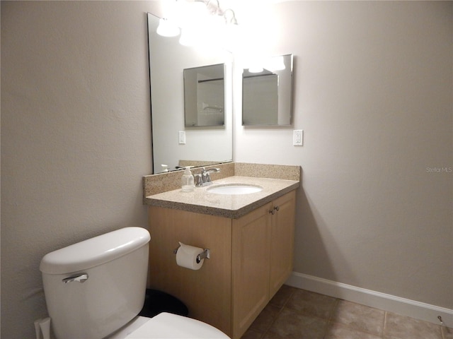 half bath with vanity, tile patterned flooring, toilet, and baseboards