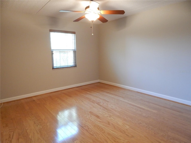 spare room with ceiling fan, light wood-style flooring, and baseboards