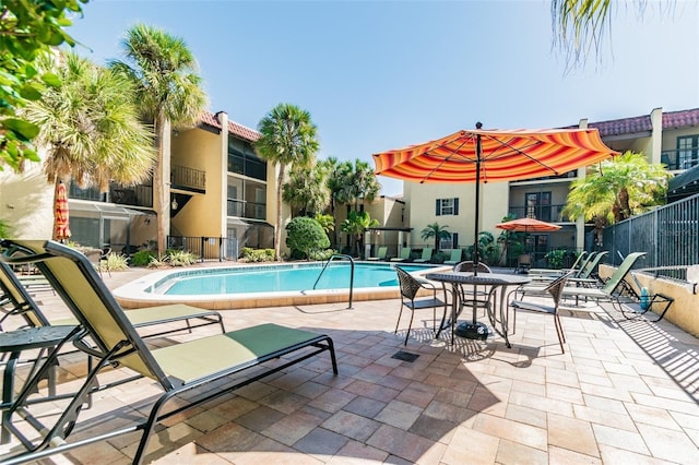 community pool with a patio area and fence