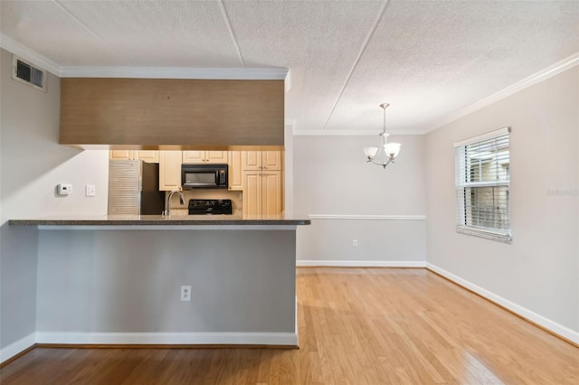 kitchen featuring dark countertops, ornamental molding, decorative light fixtures, light wood-type flooring, and black appliances