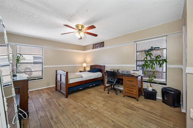 bedroom featuring ceiling fan, light hardwood / wood-style flooring, and a textured ceiling