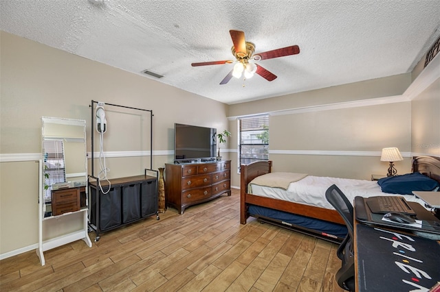 bedroom featuring a textured ceiling, light wood-type flooring, and ceiling fan