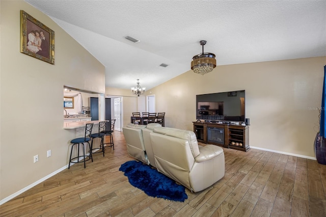 living room with hardwood / wood-style floors, lofted ceiling, and a notable chandelier