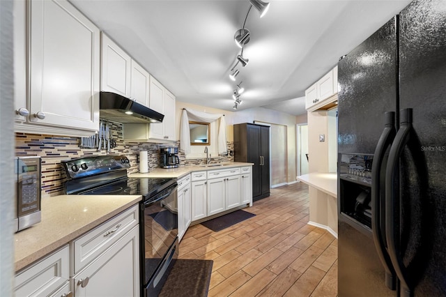 kitchen with black appliances, decorative backsplash, light hardwood / wood-style floors, and white cabinets