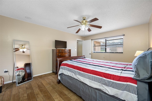 bedroom featuring hardwood / wood-style flooring, ceiling fan, cooling unit, and a textured ceiling