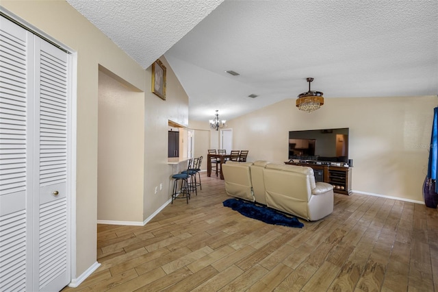 living room with hardwood / wood-style floors, lofted ceiling, and an inviting chandelier