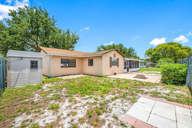 rear view of house with a fire pit, a patio area, and a storage shed