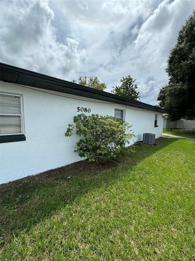 view of side of home with a yard and central AC unit