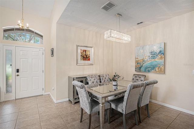 tiled dining room featuring a textured ceiling and an inviting chandelier