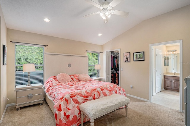 carpeted bedroom with ensuite bathroom, a walk in closet, vaulted ceiling, ceiling fan, and a closet