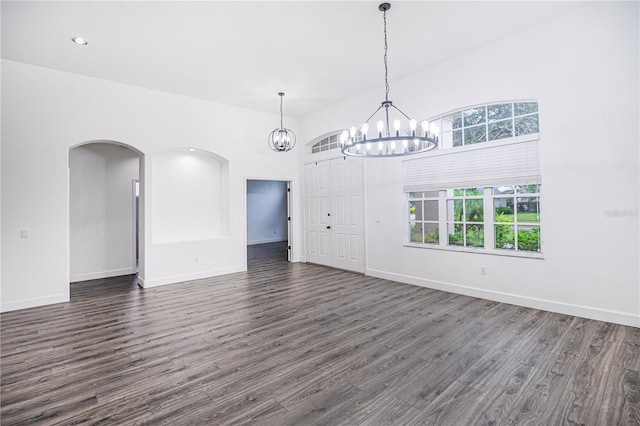 unfurnished living room featuring a notable chandelier, wood-type flooring, and a high ceiling