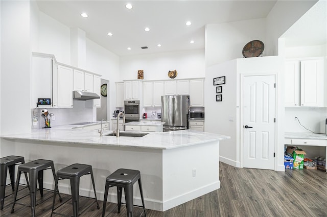 kitchen with stainless steel appliances, white cabinetry, light stone counters, wood-type flooring, and sink