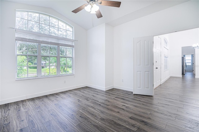 unfurnished room featuring plenty of natural light, ceiling fan with notable chandelier, lofted ceiling, and dark wood-type flooring
