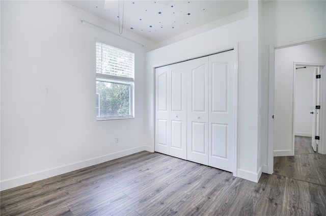 unfurnished bedroom featuring ceiling fan, a closet, and wood-type flooring