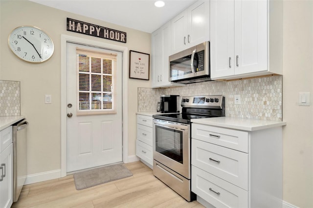 kitchen with tasteful backsplash, white cabinetry, light hardwood / wood-style floors, and appliances with stainless steel finishes