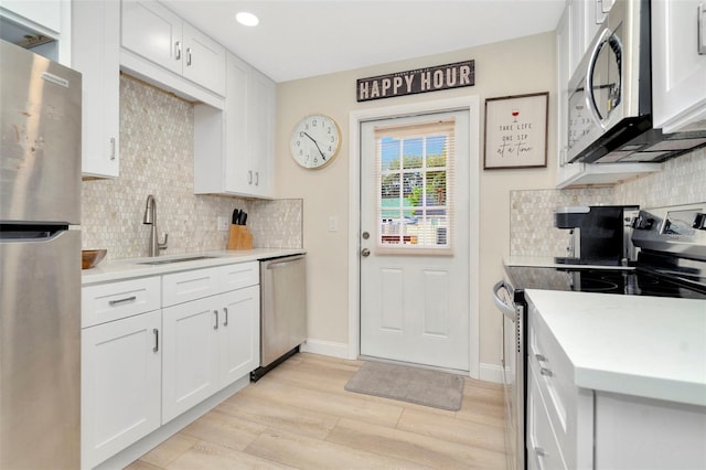 kitchen with white cabinetry, sink, appliances with stainless steel finishes, and light hardwood / wood-style flooring