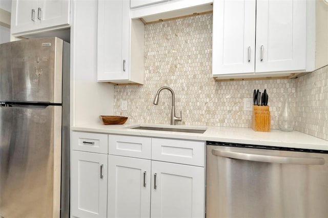 kitchen featuring decorative backsplash, stainless steel appliances, white cabinets, and sink