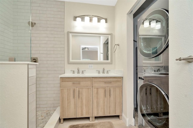 bathroom with a tile shower, vanity, stacked washing maching and dryer, and tile patterned floors