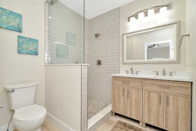 bathroom with tiled shower, vanity, toilet, and tile patterned flooring