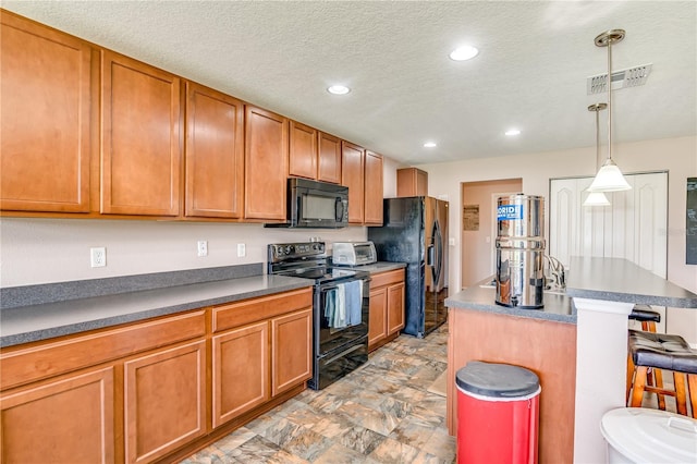 kitchen with hanging light fixtures, a textured ceiling, a breakfast bar, a kitchen island, and black appliances