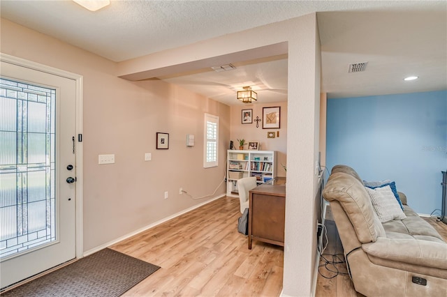 entryway with a textured ceiling and light hardwood / wood-style flooring