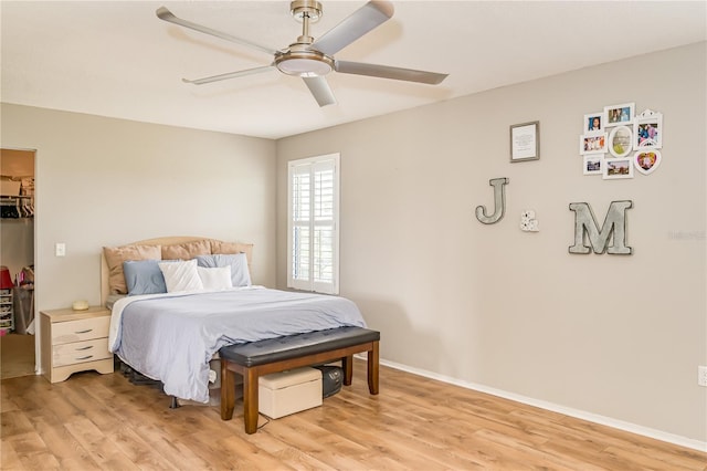 bedroom featuring ceiling fan, light hardwood / wood-style floors, and a spacious closet