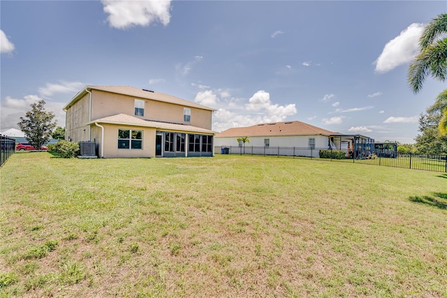 back of property with a yard and central AC