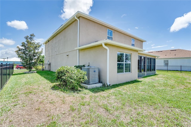 back of property with a yard and central AC