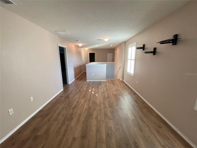 unfurnished room with a textured ceiling and dark wood-type flooring