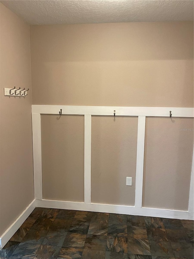 empty room with baseboards, stone finish flooring, and a textured ceiling