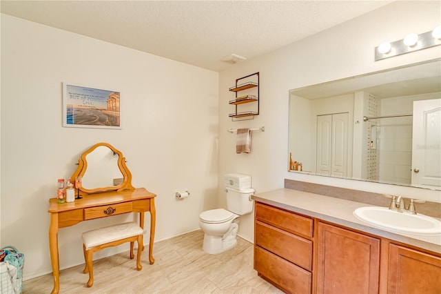 bathroom featuring toilet, vanity, baseboards, a textured ceiling, and a shower