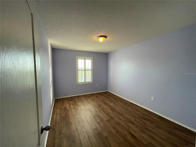 unfurnished room with wood finished floors, a textured ceiling, and baseboards