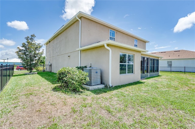 rear view of property featuring stucco siding, central air condition unit, a yard, and a fenced backyard