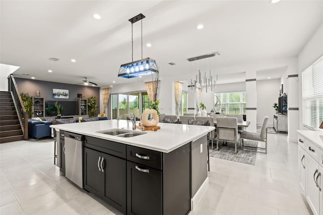 kitchen with a center island with sink, dishwasher, sink, and hanging light fixtures