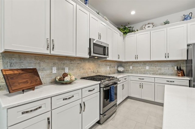 kitchen featuring light tile patterned floors, stainless steel appliances, white cabinetry, and tasteful backsplash