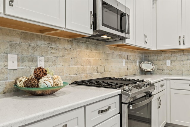 kitchen featuring decorative backsplash, stainless steel appliances, and white cabinets