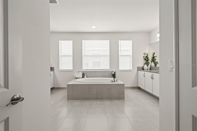 bathroom featuring vanity, a relaxing tiled tub, and tile patterned floors