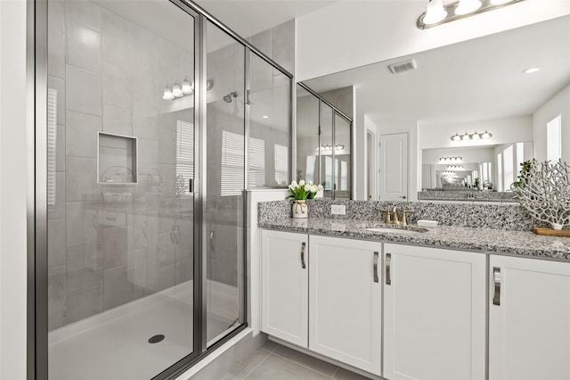 bathroom featuring tile patterned flooring, vanity, and a shower with door