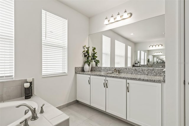 bathroom with tile patterned floors, vanity, a healthy amount of sunlight, and a washtub