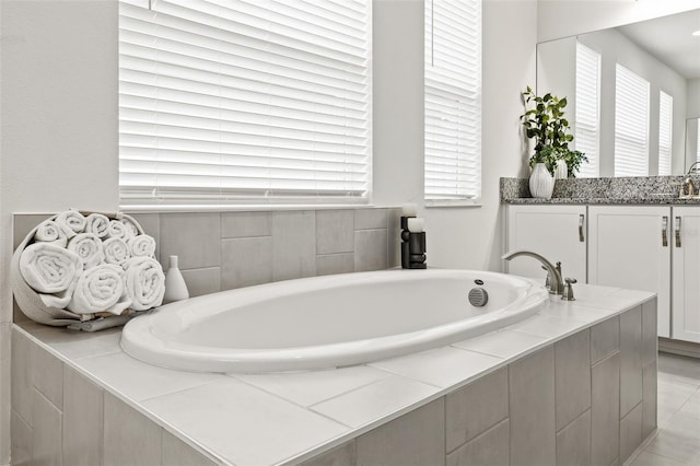 bathroom with tiled bath, tile patterned flooring, and vanity