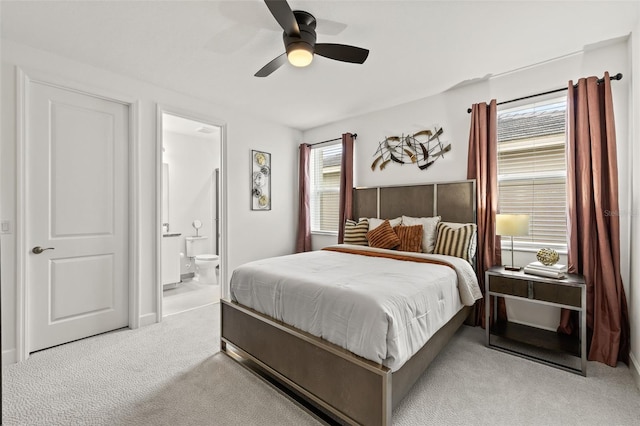 carpeted bedroom with multiple windows, ensuite bathroom, and ceiling fan