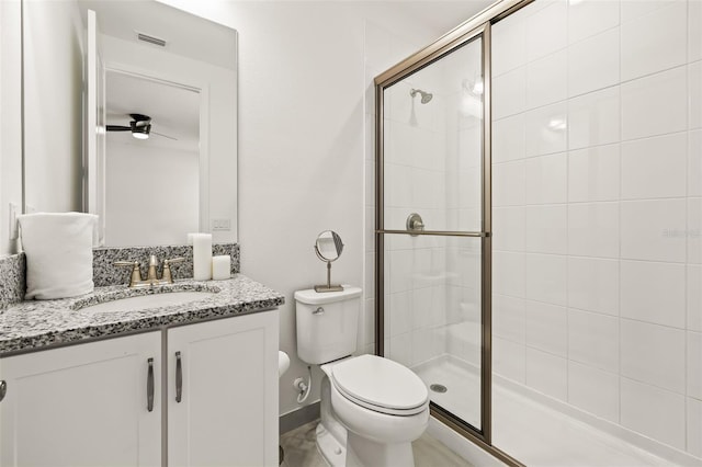 bathroom featuring ceiling fan, vanity, a shower with shower door, and toilet