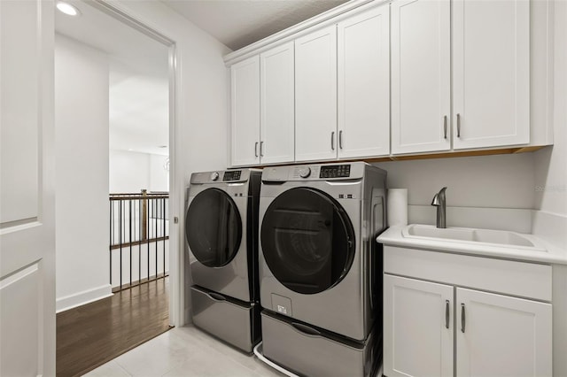 laundry area with cabinets, light tile patterned flooring, washer and clothes dryer, and sink