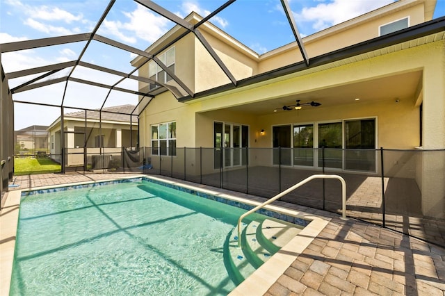 view of pool with glass enclosure, ceiling fan, and a patio area