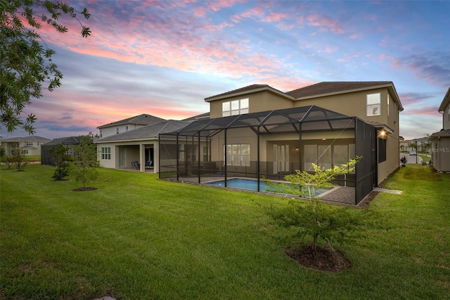 back house at dusk with a lawn, a lanai, and a patio