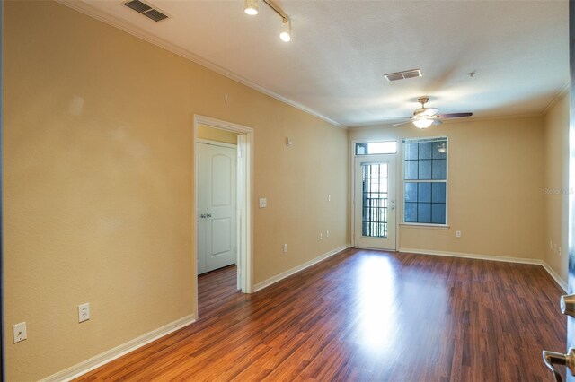 spare room with ornamental molding, visible vents, and dark wood finished floors